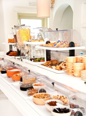 A buffet setup with various food items and beverages in clear containers. - Altana Boutique Hotel (Tinos)