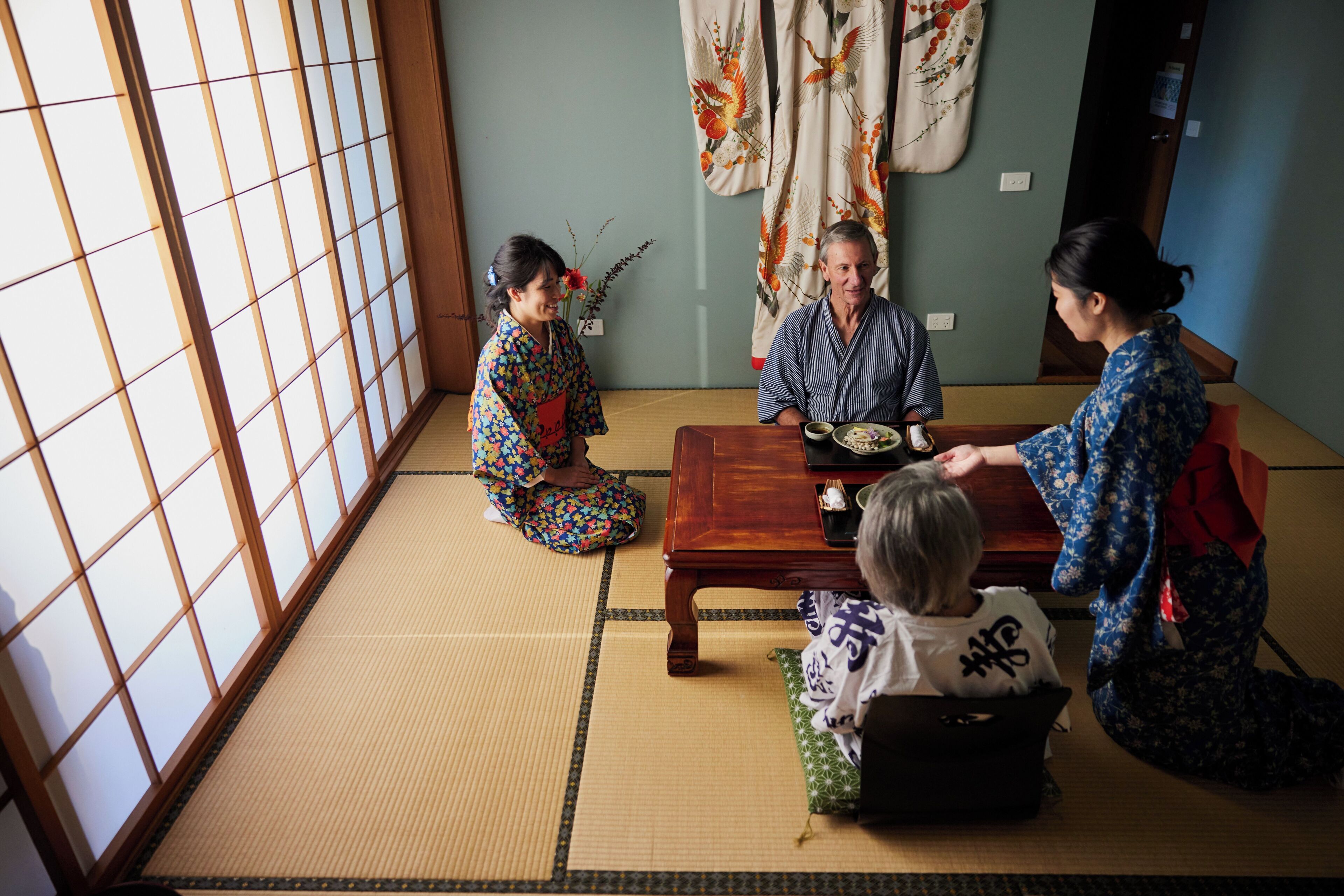 Una habitación japonesa tradicional con suelo de tatami, una mesa de madera baja y puertas correderas shoji.