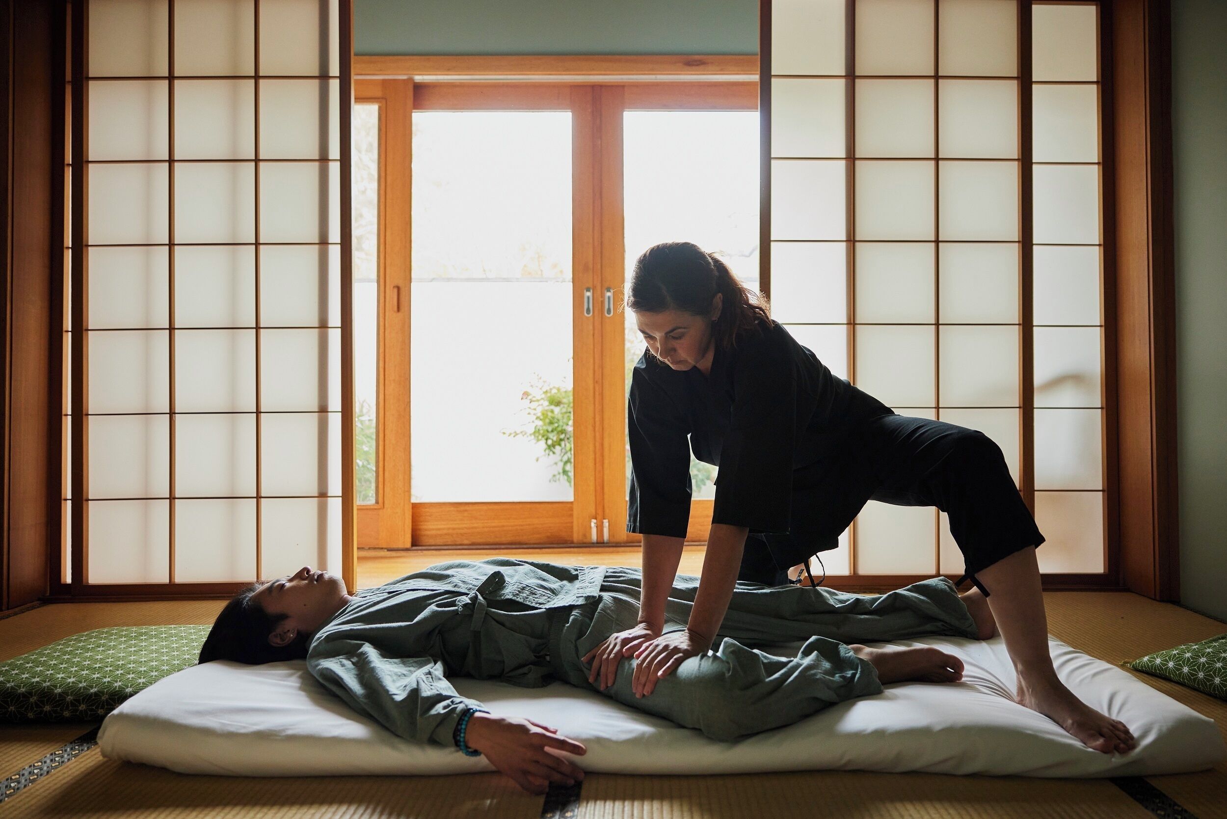 A traditional Japanese room with tatami flooring, shoji screens, and a futon bed.
