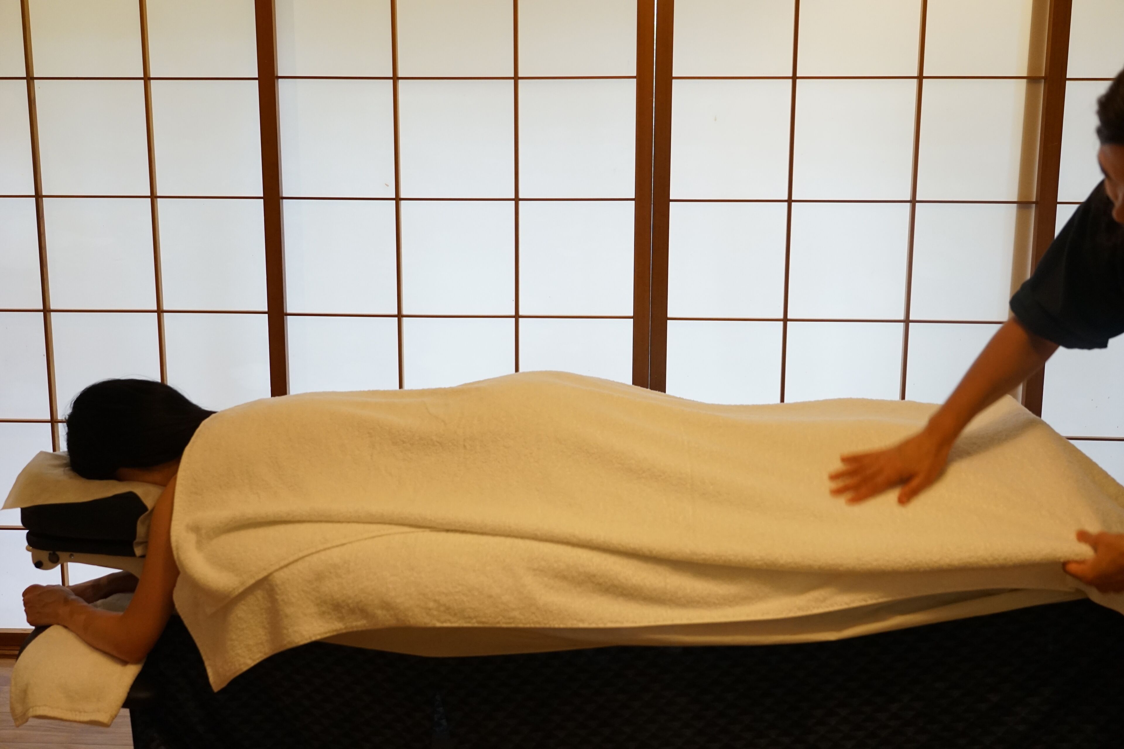 A room with a tatami mat floor, a low table, and a shoji screen in the background.