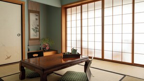 A traditional Japanese room with tatami flooring, a wooden table, and a sliding shoji screen. - Shizuka Ryokan Japanese Country Spa & Wellness Retreat (Hepburn)