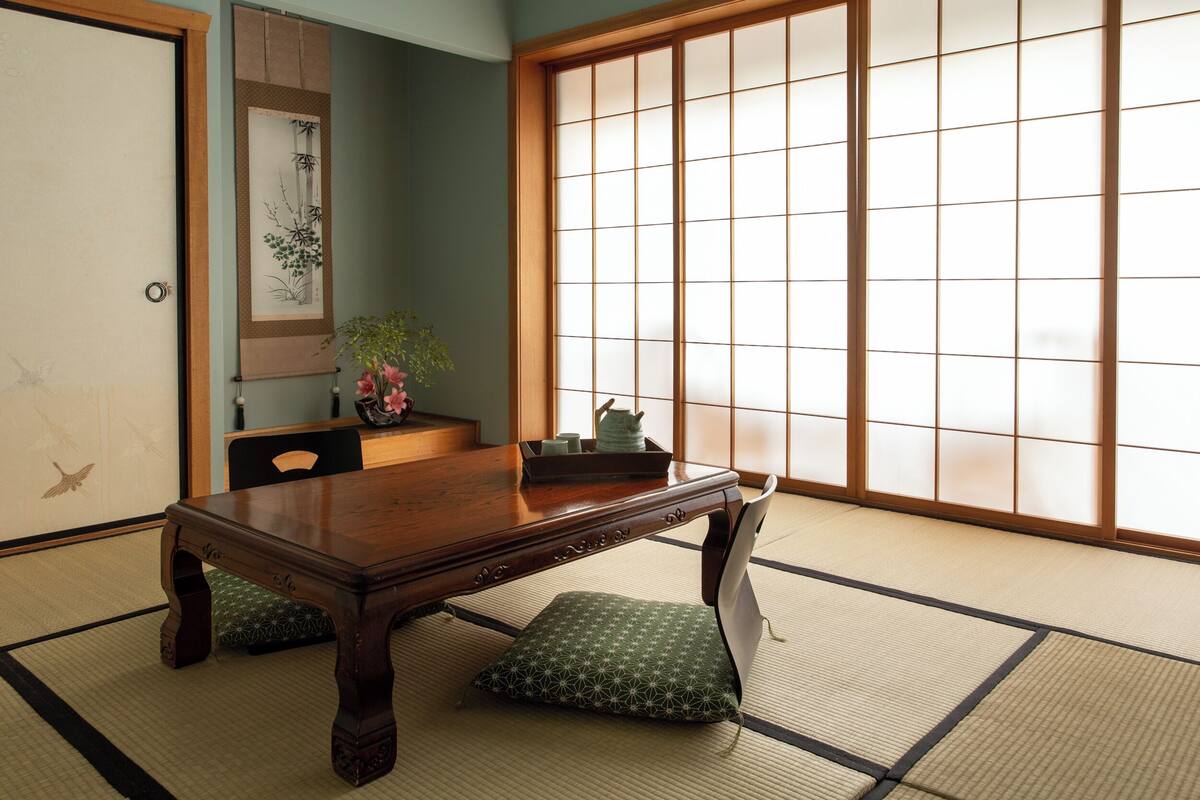Una habitación japonesa tradicional con suelo de tatami, una mesa de madera y un panel corredizo shoji.
