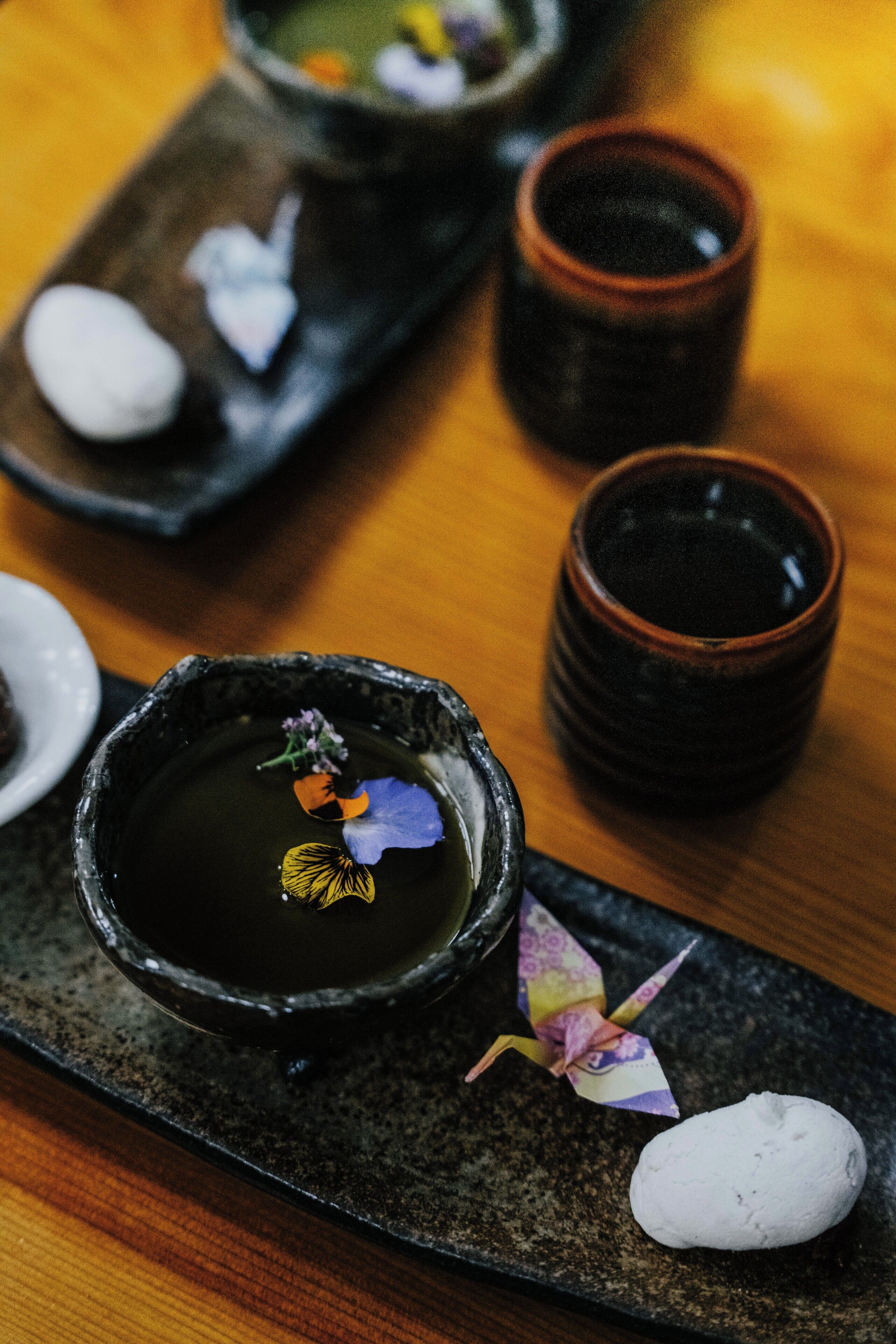 A traditional Japanese tea ceremony setup with a tea bowl, matcha, and a decorative flower.