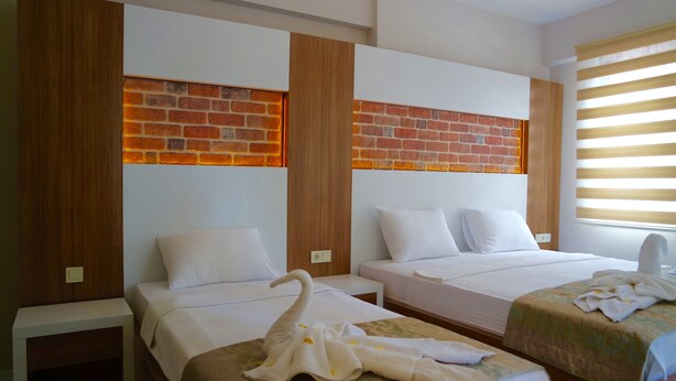 A hotel room with two beds, a brick accent wall, wooden paneling, and a window with blinds. - Ale Boutique Hotel (Konyaalti)