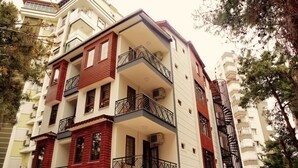 A multi-story residential building with balconies, air conditioning units, and a brick facade. - Ale Boutique Hotel (Konyaalti)