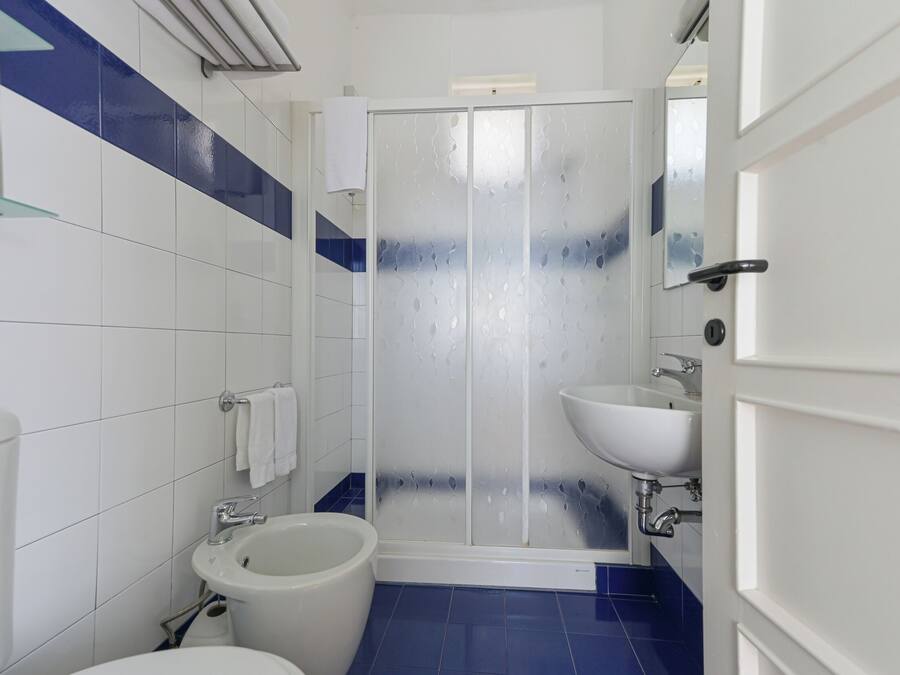 Une salle de bain comprenant des toilettes, un bidet, un lavabo et une douche à parois en verre.