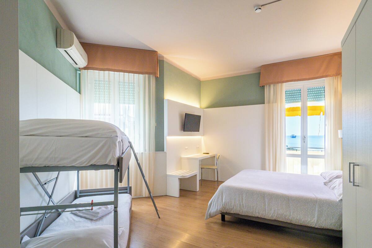 A room with bunk beds, a desk, a chair, and a bed.