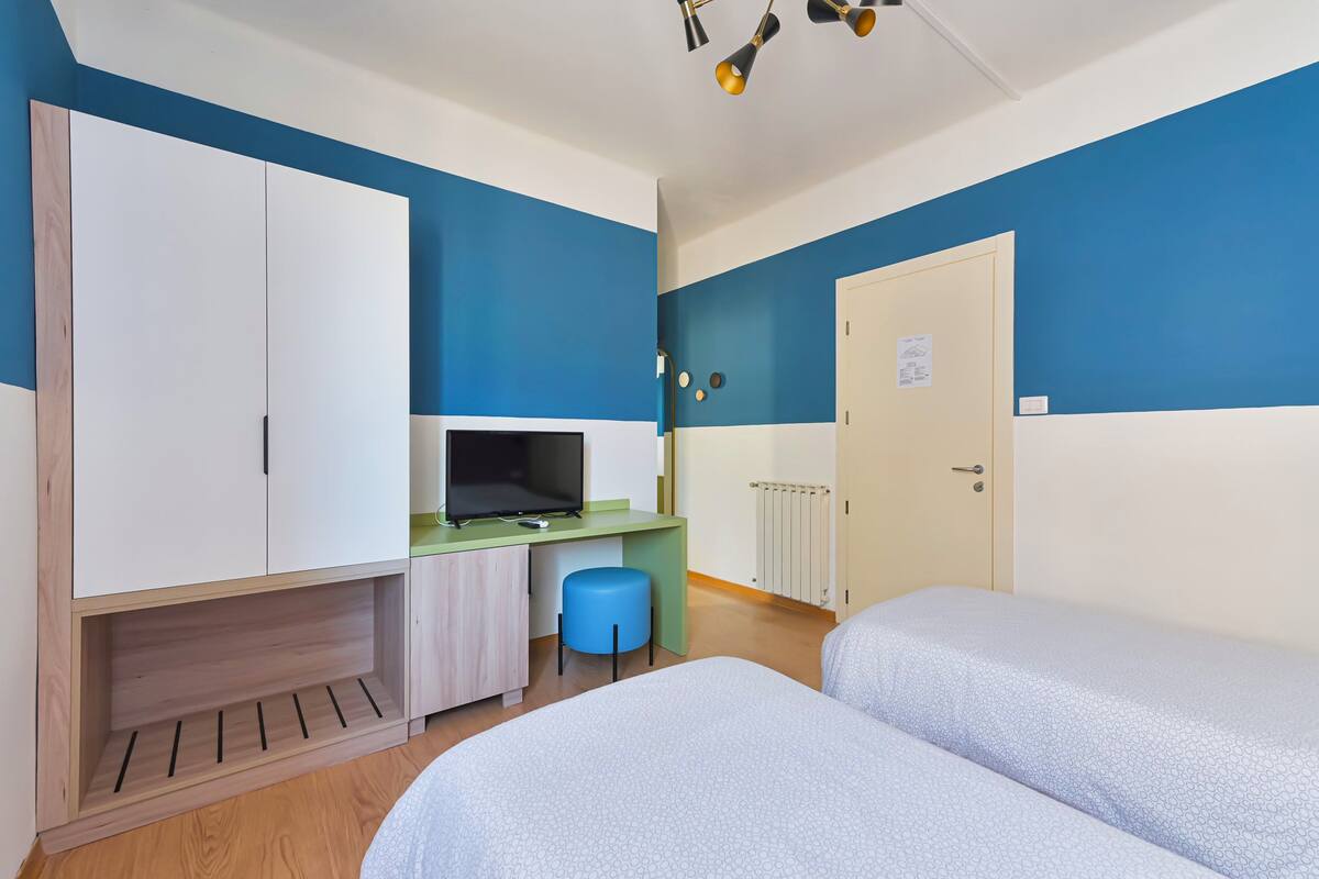 A room with two beds, a desk, a television, and a wardrobe.