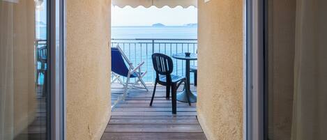 Una terraza de madera con vista al mar, una silla y una mesa.