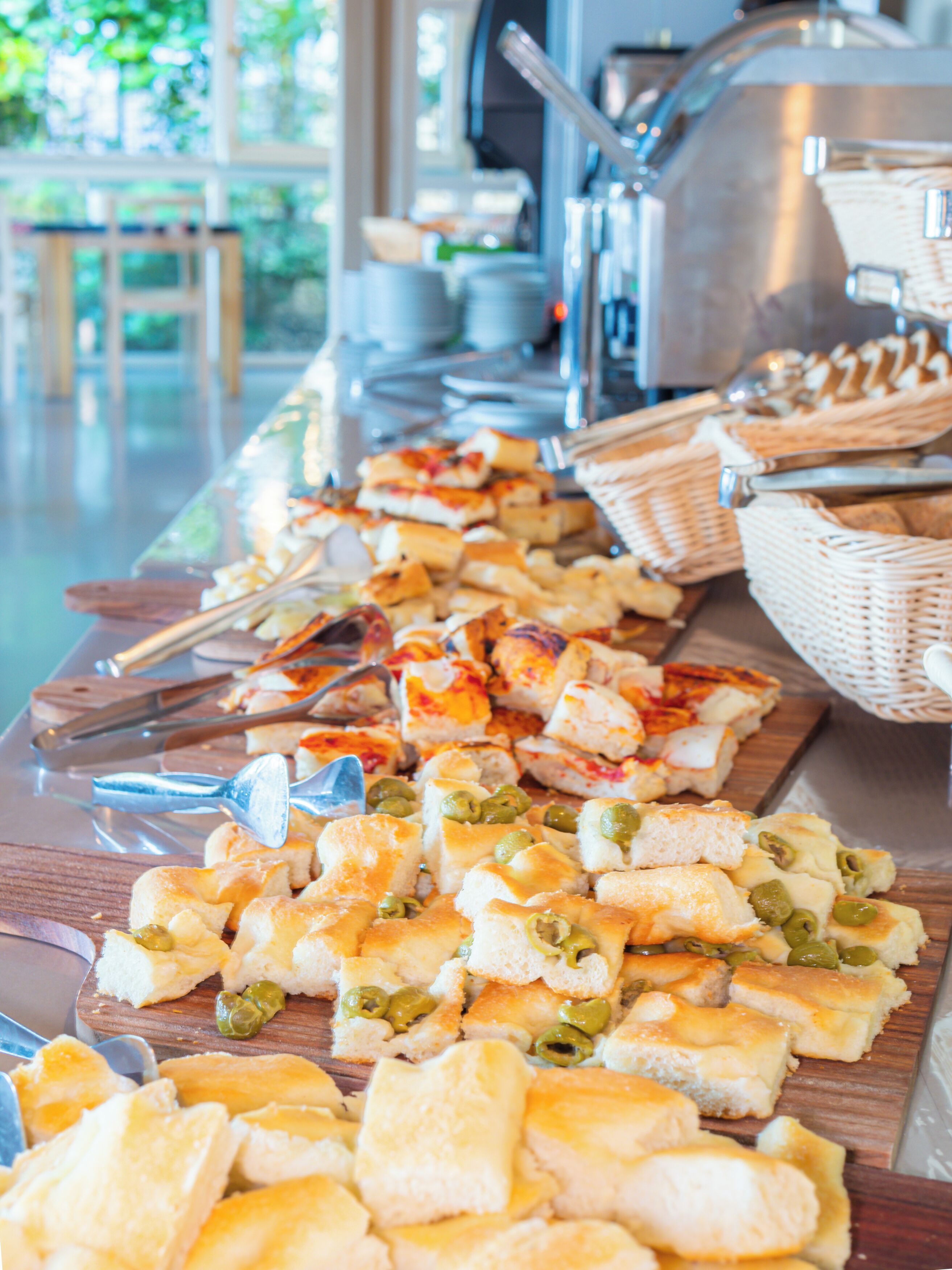 A buffet table with various food items, including bread and olives.