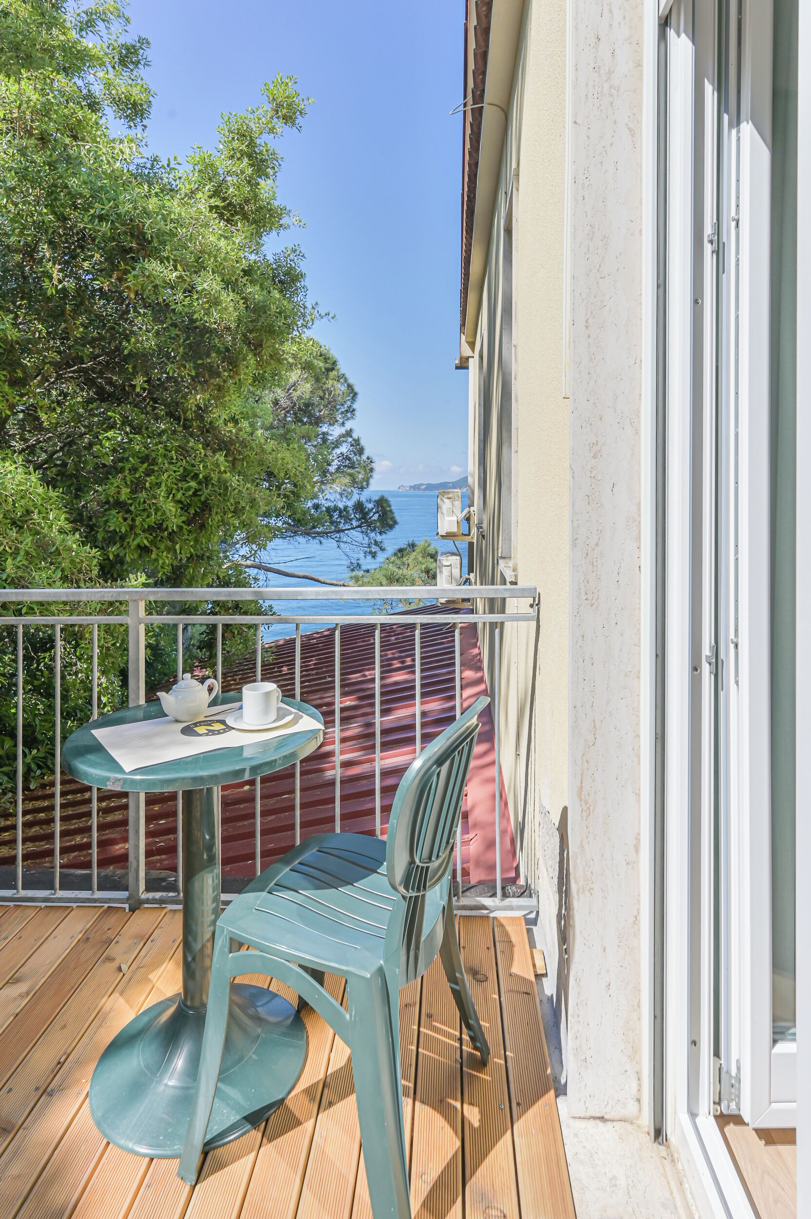 Een balkon met een tafel, stoelen en uitzicht op zee.