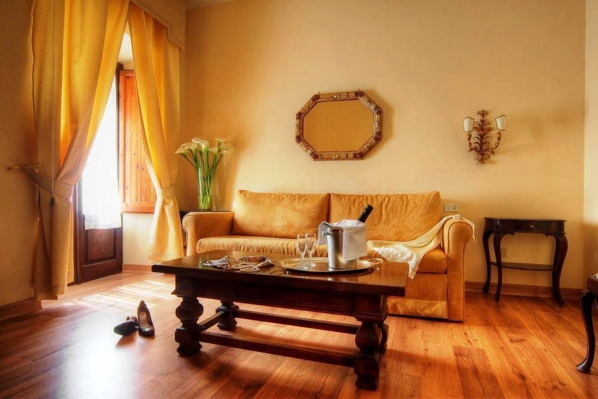 A living room with a wooden coffee table, a sofa, a mirror, and a lamp.