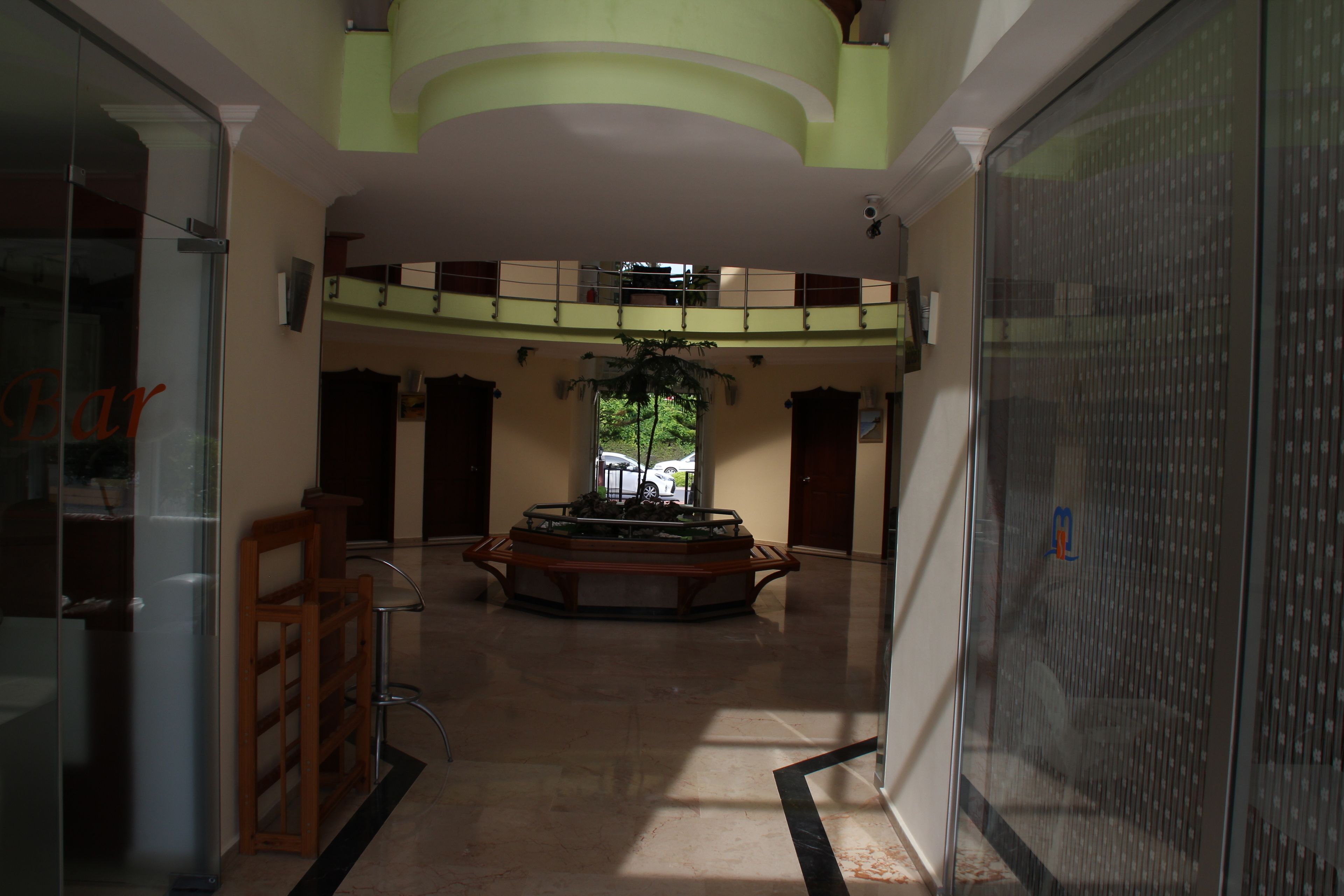 Eine geräumige Lobby mit einer zentralen Fontäne, einer Glaswand links und einem großen Fenster am Ende.