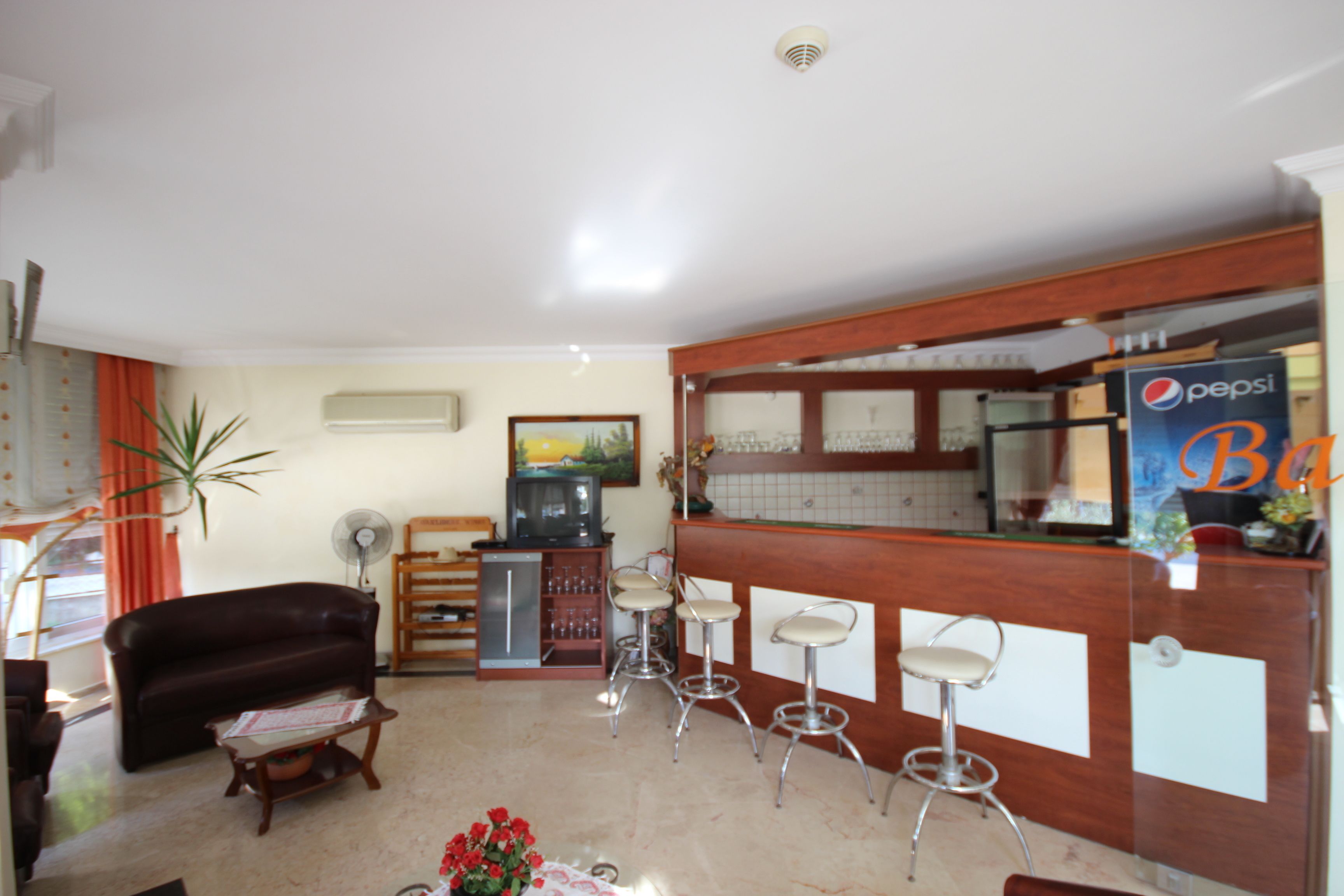 A living room with a brown leather sofa, a wooden coffee table, and a bar area with a Pepsi sign.