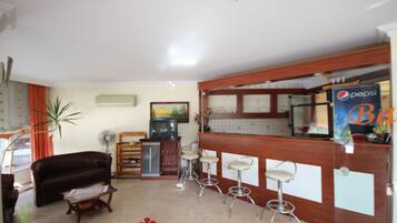 A living room with a brown leather sofa, a wooden coffee table, and a bar area with a Pepsi sign.