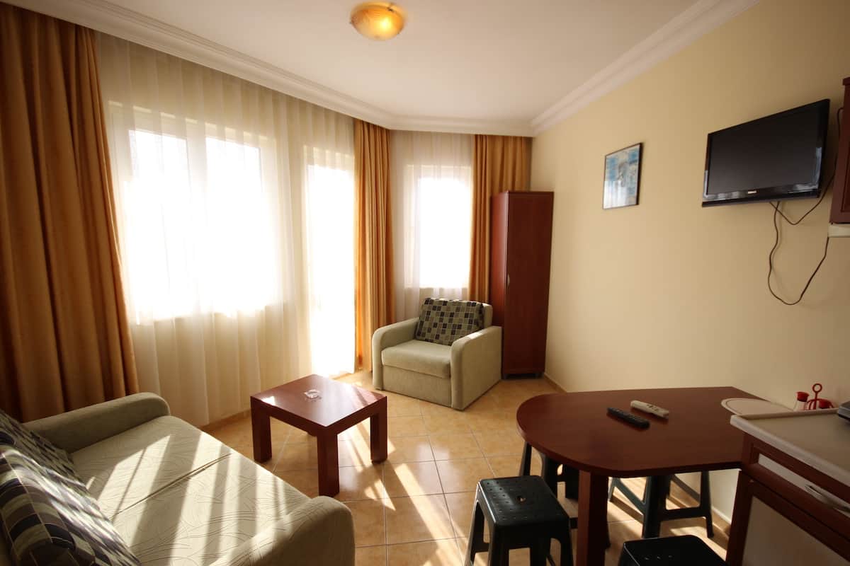 A living room with a sofa, a small table, a chair, a TV, and a cabinet.