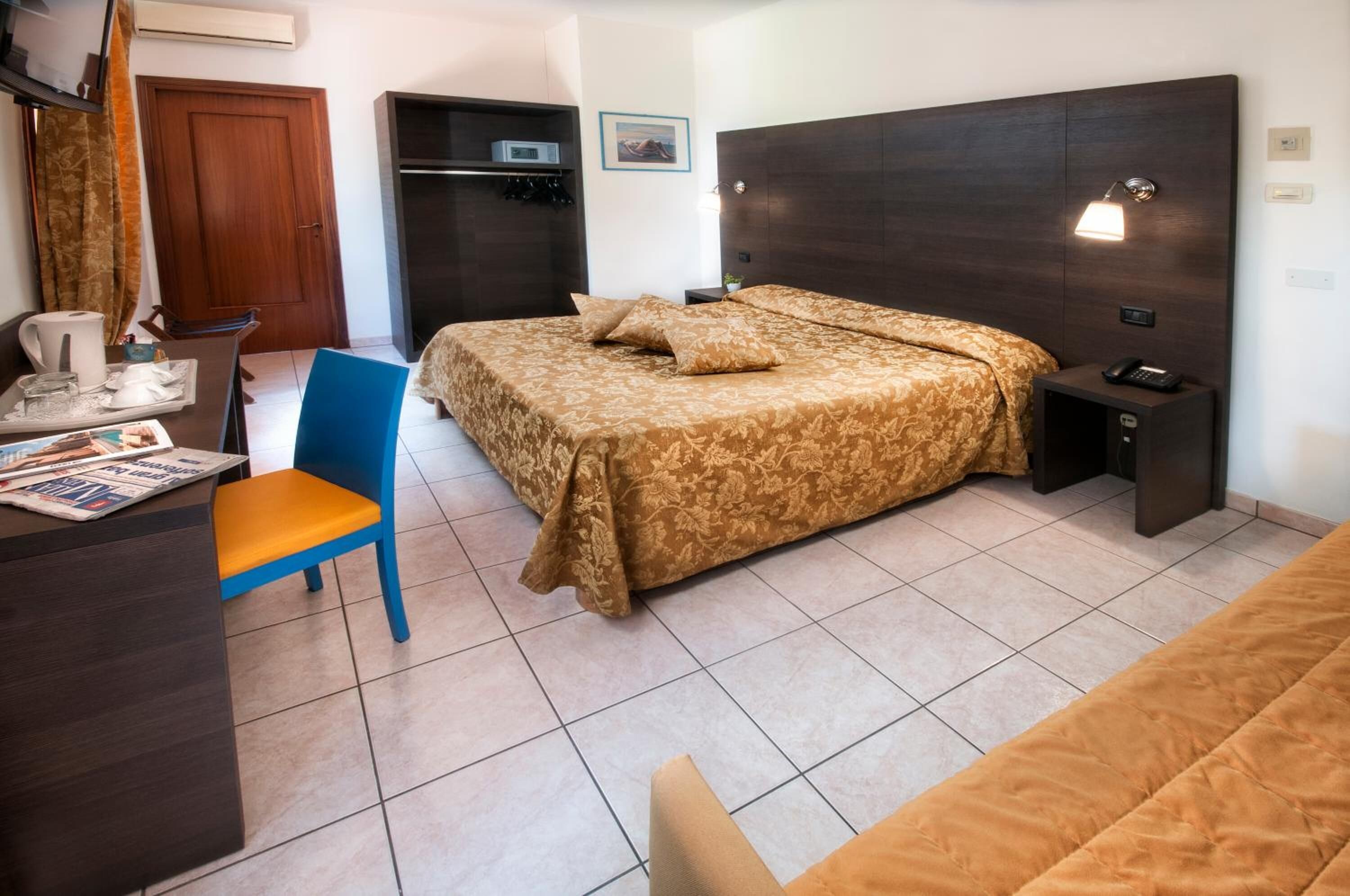 Ein Hotelzimmer mit Bett, Schreibtisch, Stuhl, Kleiderschrank und Tür.