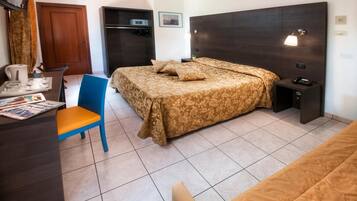 Ein Hotelzimmer mit Bett, Schreibtisch, Stuhl, Kleiderschrank und Tür.