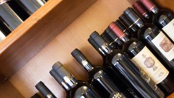 Un porte-bouteilles en bois contenant plusieurs bouteilles de vin, dont des marques comme Casillero del Diablo et Stainbeck.