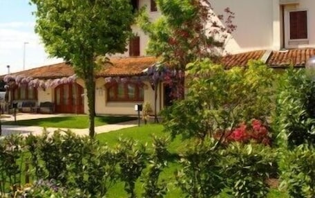 A traditional building with a thatched roof, surrounded by well-maintained gardens and a clear sky.
