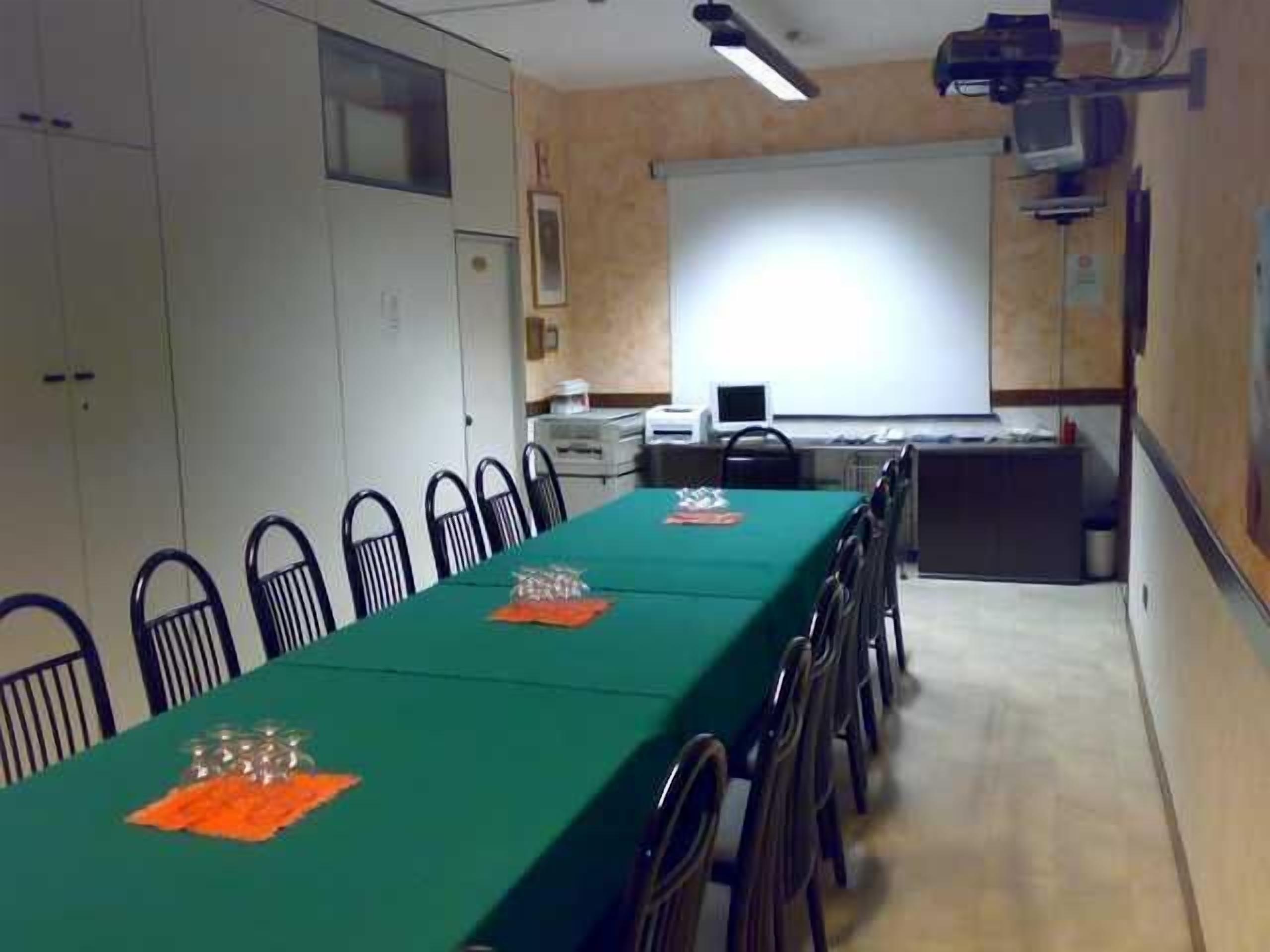 A conference room with a long table, chairs, a projector, and a screen.