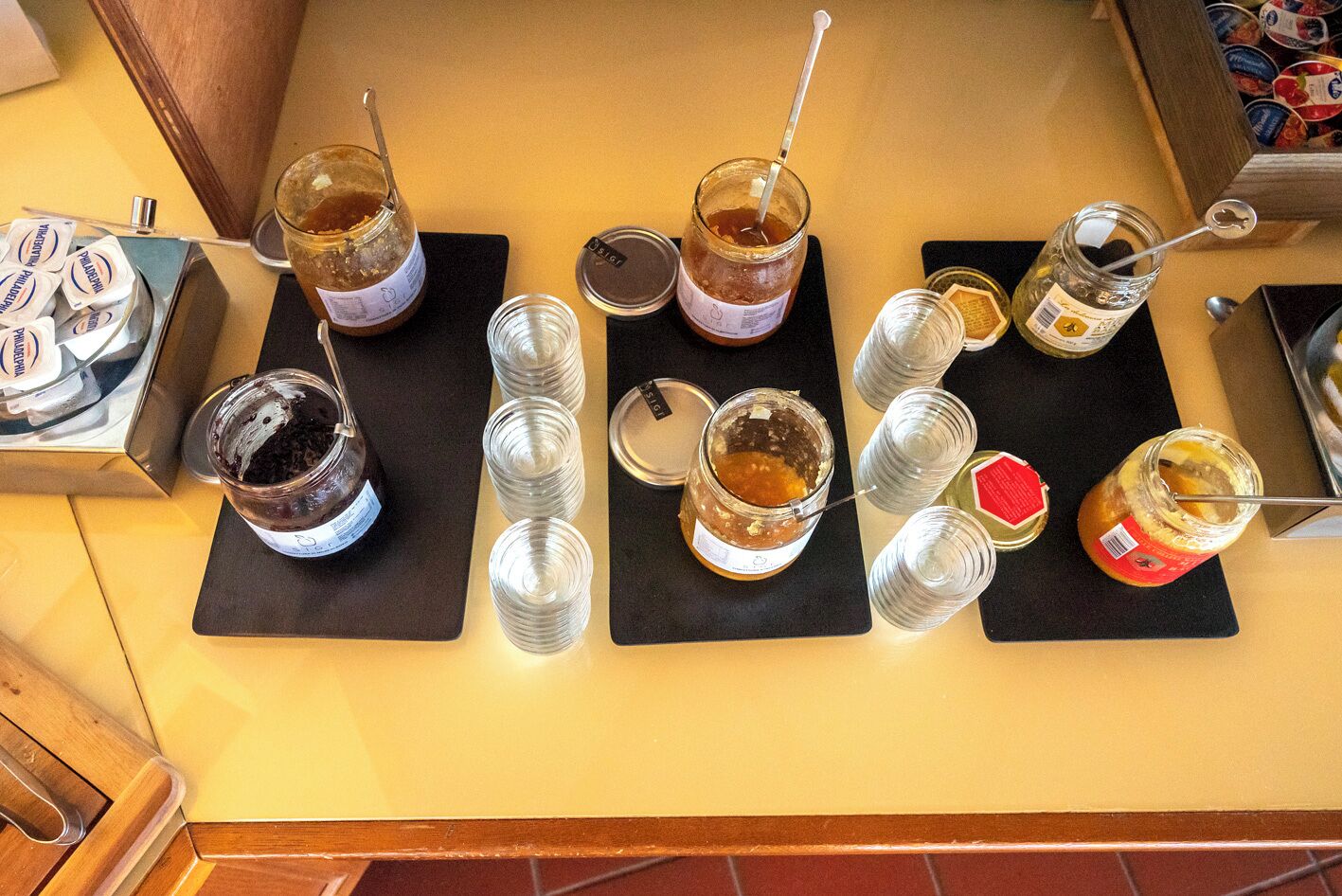 Un comptoir où sont disposés divers pots contenant des condiments et du miel, certains avec des couvercles et d’autres ouverts.