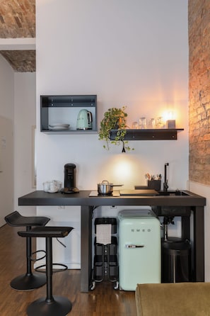A compact kitchen with a coffee machine, a vintage-style refrigerator, and a bar stool. - Hotel Johann (Berlin)