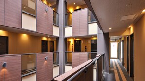 A hotel corridor with wooden paneling, a metal railing, and a carpeted floor with a geometric pattern. - APA Hotel Ningyocho Ekikita (Tokyo)