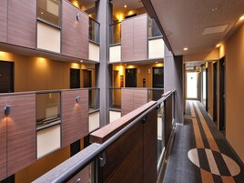 Un pasillo de hotel con paneles de madera, una barandilla de metal y un suelo alfombrado con diseño geométrico.