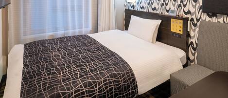 Une chambre d’hôtel avec un grand lit, une table de chevet avec une lampe et un mur décoré d’un motif.