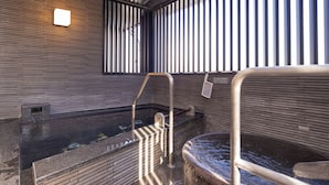 Un área de spa con una bañera de hidromasaje, una escalera de metal y una ventana con persianas verticales.