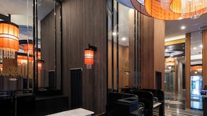Un vestíbulo de hotel moderno con mostradores de mármol, paneles de madera y un candelabro.