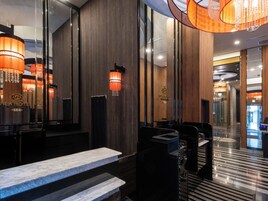 Un vestíbulo de hotel moderno con mostradores de mármol, paneles de madera y un candelabro.