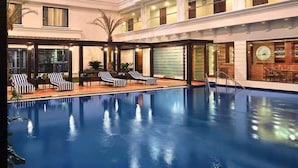 A multi-level indoor swimming pool with lounge chairs and a bar area. - Fortune JP Palace, Mysore - Member ITC Hotels' Group (Mysore)
