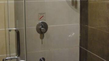 Un baño con puerta de vidrio, ducha y barra para toallas.