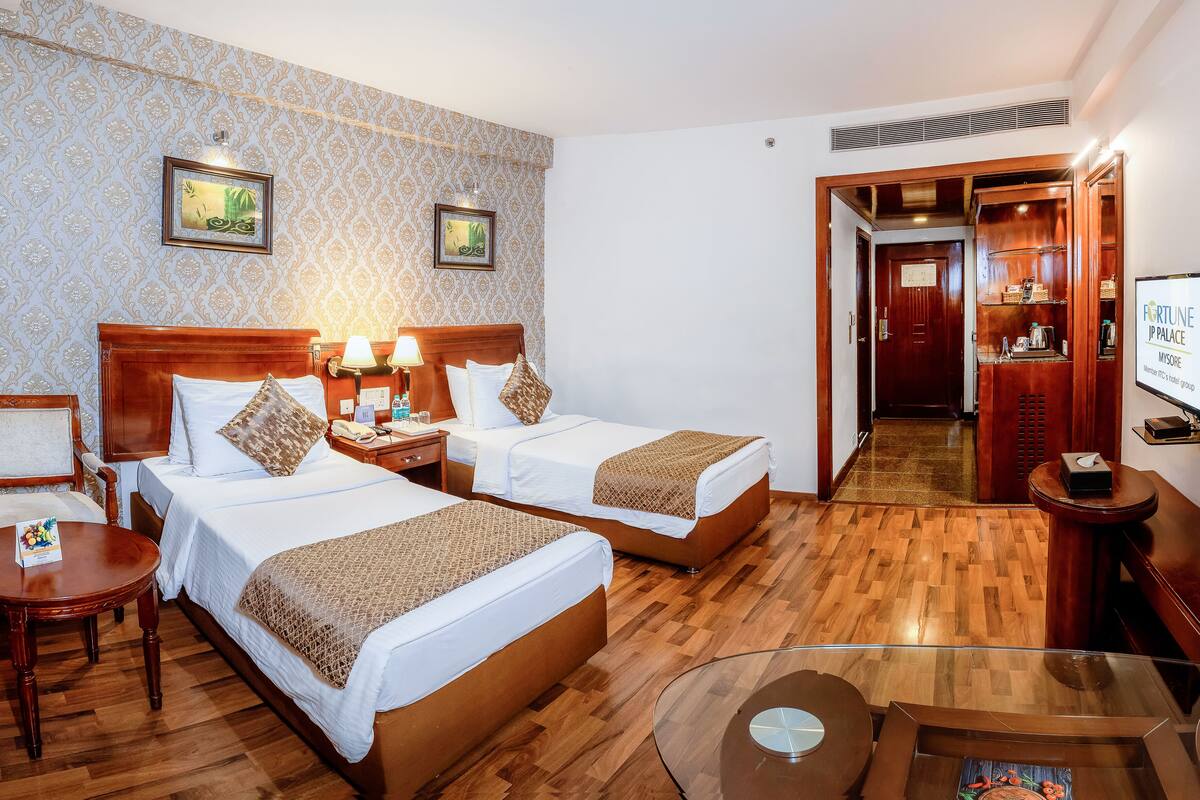 Une chambre d’hôtel avec deux lits, un plancher en bois, un bureau et une télévision.