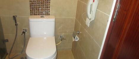 A bathroom with a toilet, a shower, and a hand dryer.