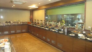 Ein reichhaltiges Buffet mit mehreren Speiseauslagen und einem Koch im Hintergrund.