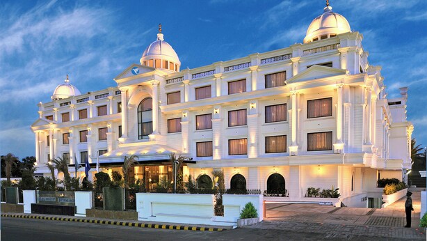 Ein prächtiges Hotel mit mehreren Kuppelbauten, einer gut beleuchteten Fassade und einem repräsentativen Eingang.