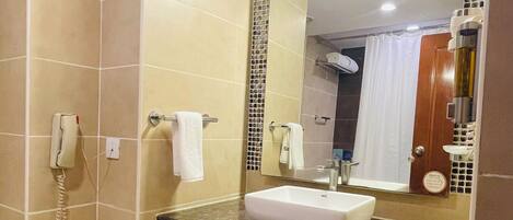A bathroom with a white sink, a mirror, a telephone, and a trash bin.