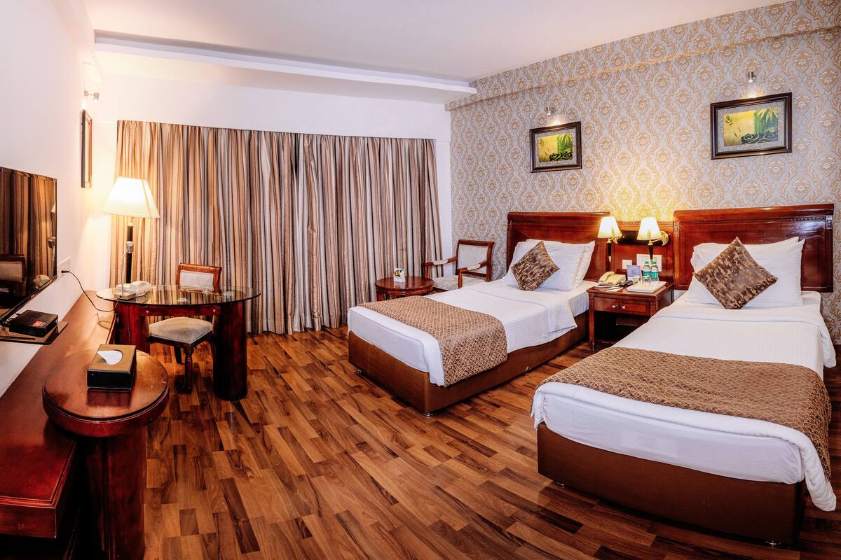 Une chambre d’hôtel avec deux lits, un bureau, une chaise et un téléviseur.