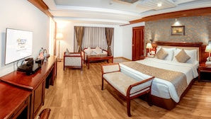 A hotel room with a bed, two chairs, a desk, a TV, and a wall with curtains. - Fortune JP Palace, Mysore - Member ITC Hotels' Group (Mysore)