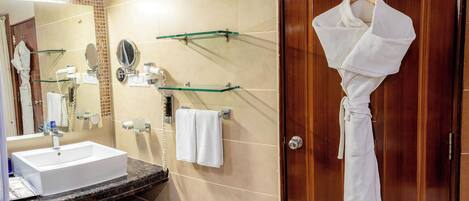 A bathroom with a sink, mirror, towel rack, and a robe hanging on a door.