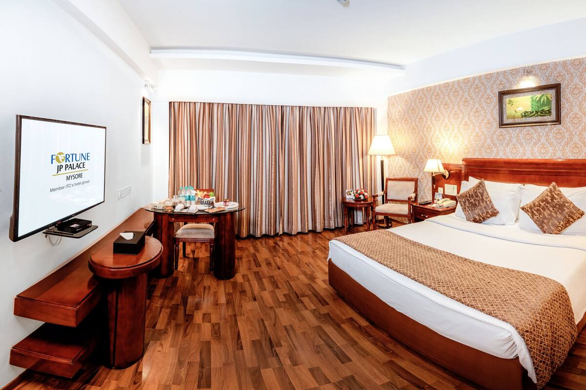 Une chambre d’hôtel avec un grand lit, un bureau avec une chaise, une télévision et un tableau accroché au mur.