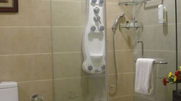 A modern bathroom with a glass-enclosed shower, a toilet, and a glass shelf with toiletries.
