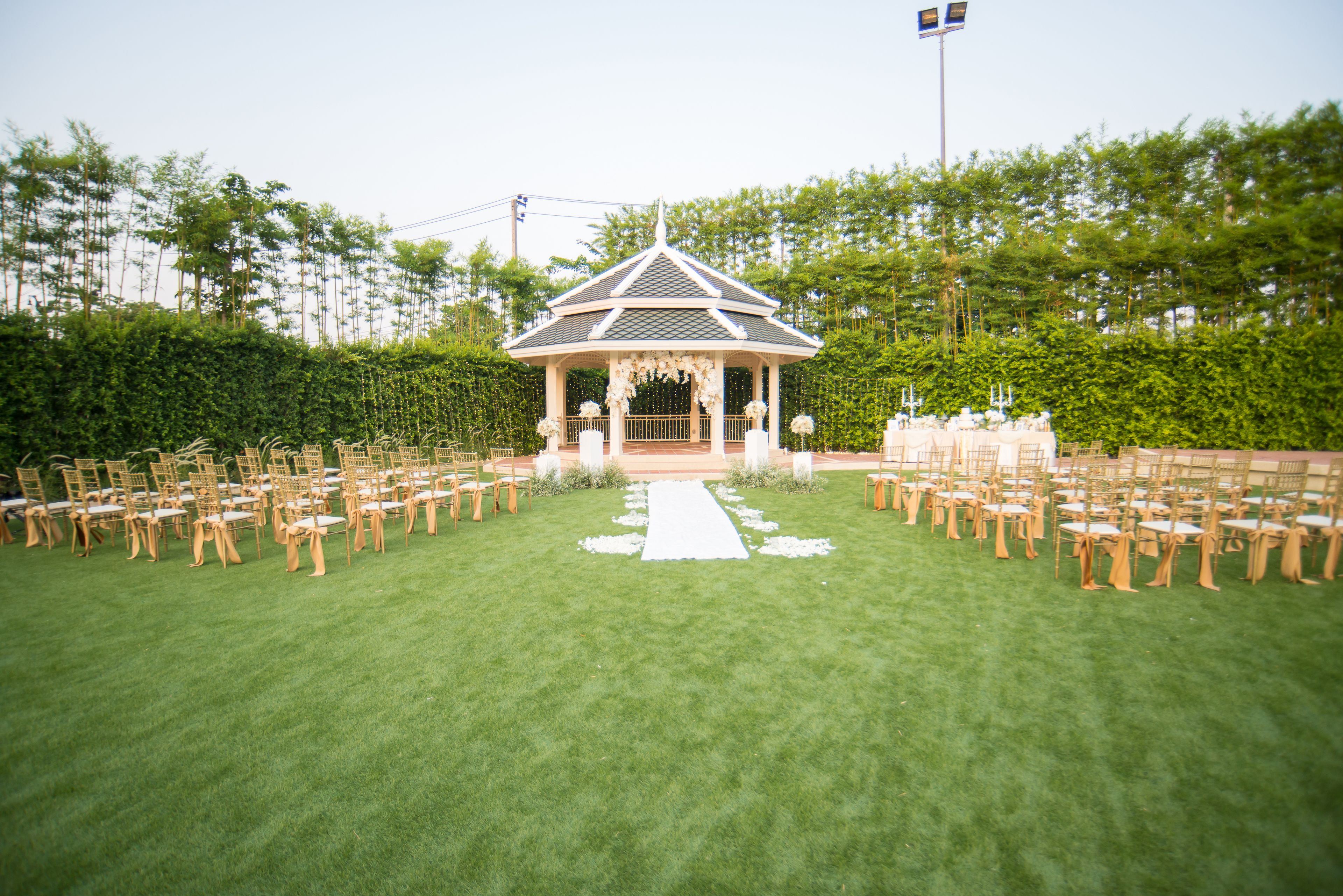 A gazebo-style wedding venue with a white aisle and chairs arranged on either side.