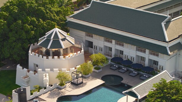 Een resort met een zwembad, loungegedeeltes en een kasteelachtige structuur.