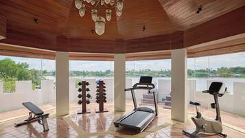 A gym with exercise equipment, large windows, and a view of a lake.