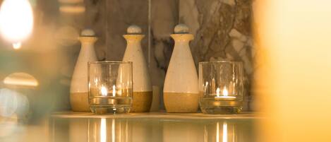 A bathroom with three glass bottles and two glasses on a reflective surface.