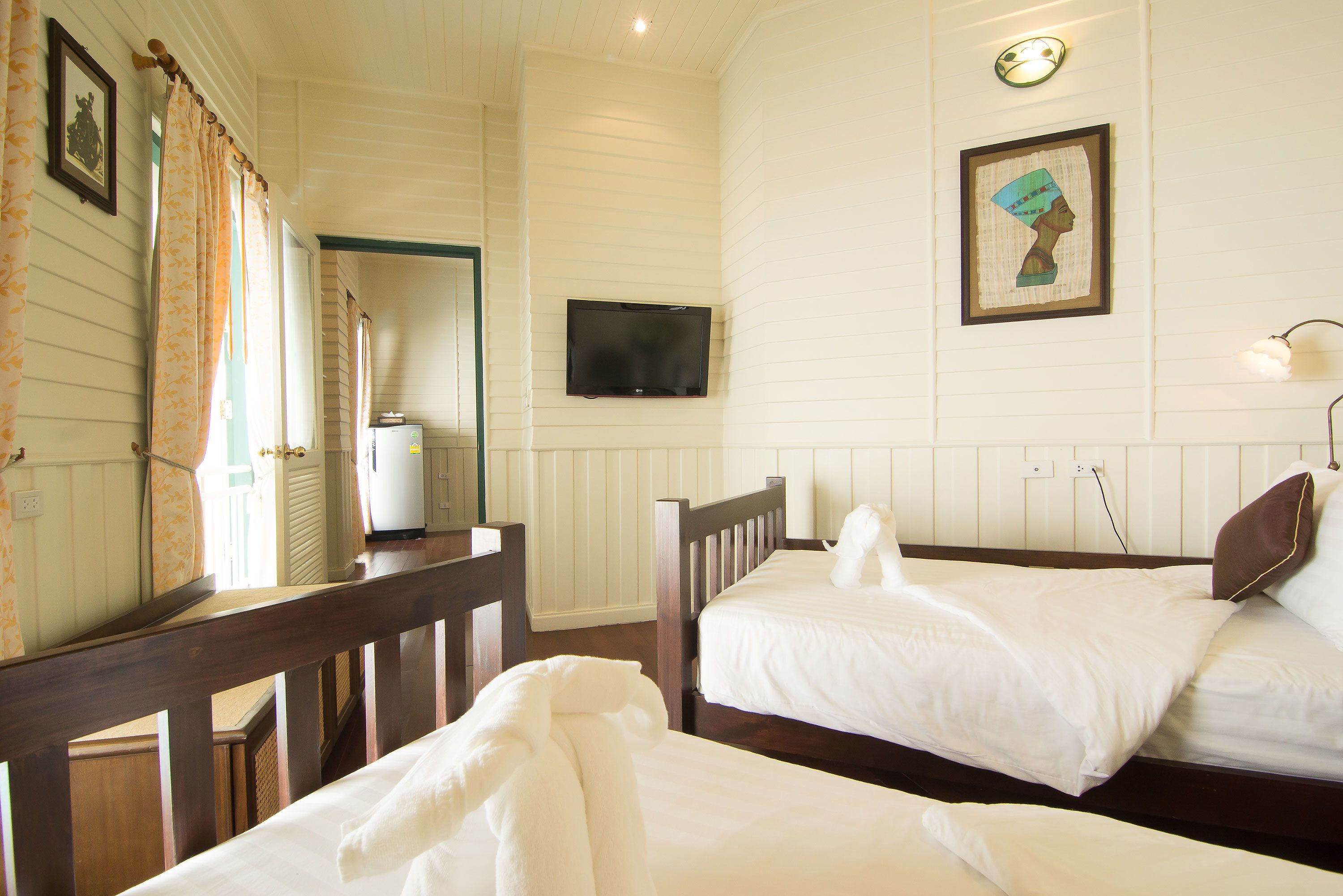 A hotel room with two beds, a television, and a framed artwork on the wall.